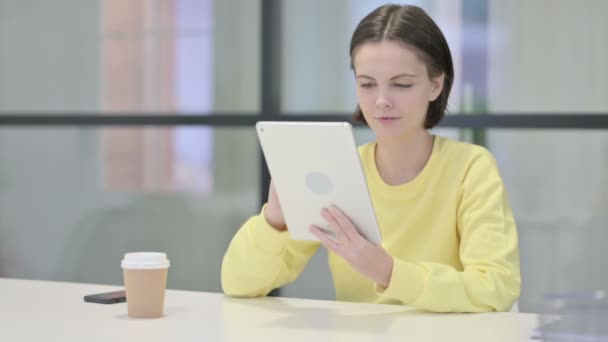 Mujer joven usando Tablet mientras está sentada en la oficina — Vídeos de Stock
