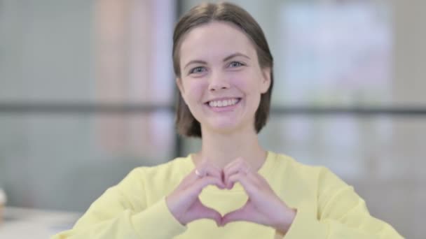 Retrato da jovem mulher mostrando a forma do coração por mãos — Vídeo de Stock