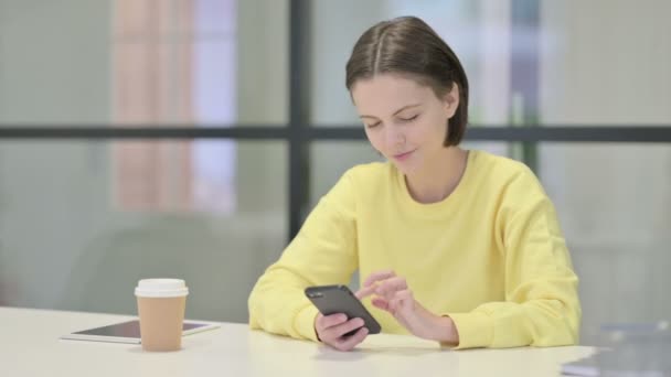 Mladá žena pomocí chytrého telefonu v kanceláři — Stock video