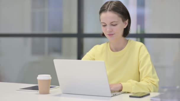 Молодая женщина показывает пальчики вверх знак при использовании ноутбука в офисе — стоковое видео