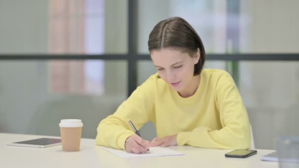 Jovem mulher escrevendo sobre papel no escritório — Vídeo de Stock