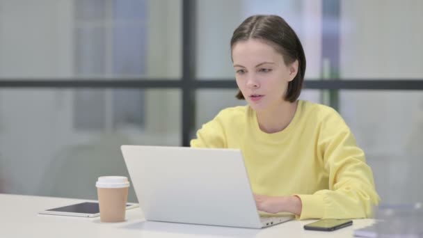 Jovem mulher comemorando o sucesso ao usar o laptop no escritório — Vídeo de Stock