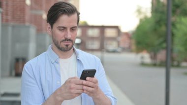 Açık havada dururken Akıllı Telefon kullanan adam