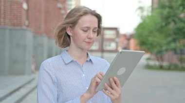 Sokakta yürürken tablet kullanan genç kadın.