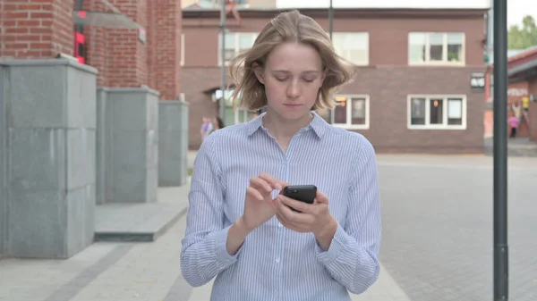 Frau benutzt Smartphone beim Gehen auf der Straße — Stockfoto