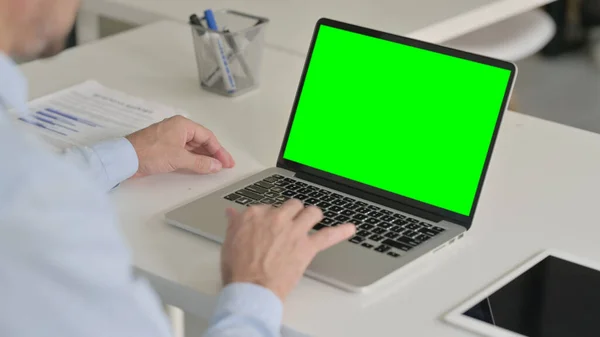 Человек средних лет с помощью ноутбука с зеленым хромовым экраном — стоковое фото