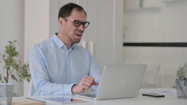 Ofiste dizüstü bilgisayar kullanırken Orta Yaşlı Adam Kayıplara Tepki Veriyor