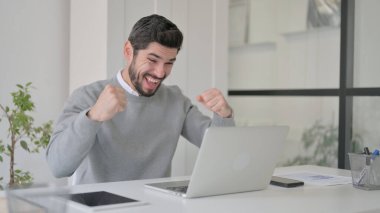 Ofiste dizüstü bilgisayar kullanırken Başarı Kutlaması Genç Adam