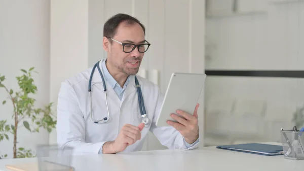 Middelbare leeftijd Doctor praten op video gesprek op tablet in de kliniek — Stockfoto