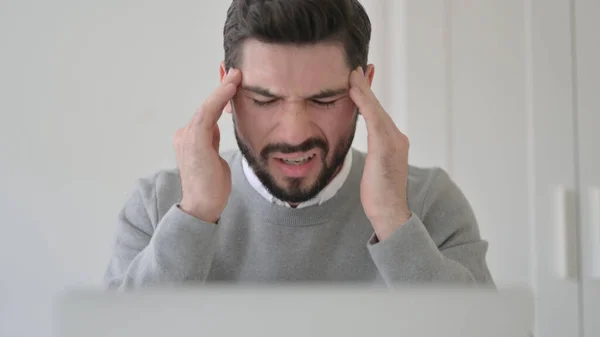 Nahaufnahme eines jungen Mannes, der Kopfschmerzen hat, während er Laptop benutzt — Stockfoto