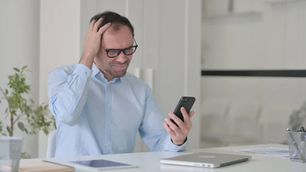 Verärgerter Mann mittleren Alters reagiert auf Verlust am Smartphone — Stockfoto