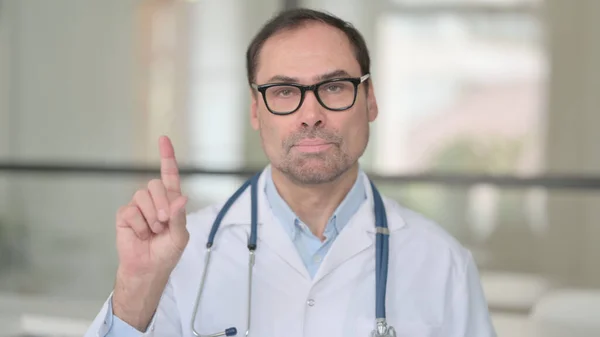 Літній лікар, який не виявляє ознак пальцями — стокове фото