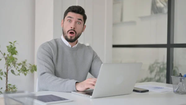 Junger Mann steht unter Schock, als er Laptop im Büro benutzt — Stockfoto