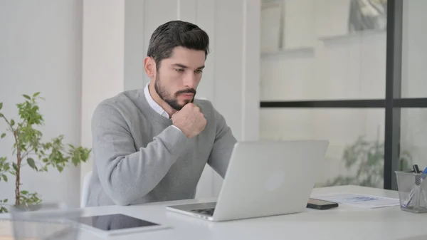 Fiatalember gondolkodás közben dolgozik Laptop az irodában — Stock Fotó