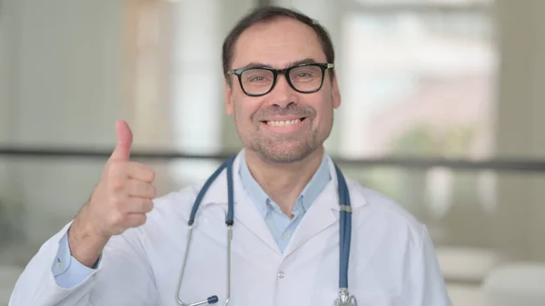 Доктор средних лет показывает большой палец вверх знак — стоковое фото