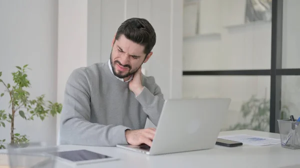 Junger Mann hat Nackenschmerzen, während er Laptop im Büro benutzt — Stockfoto