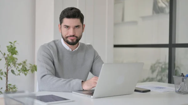 Giovane uomo scuotendo la testa come nessun segno durante l'utilizzo del computer portatile in ufficio — Foto Stock