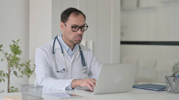 Médico de meia-idade trabalhando no laptop na clínica — Fotografia de Stock