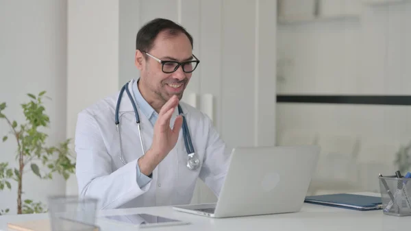 Médico de meia-idade falando sobre chamada de vídeo no laptop na clínica — Fotografia de Stock