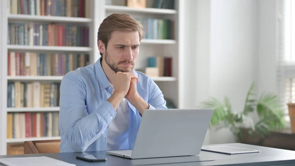 Uomo Pensando mentre si lavora sul computer portatile in ufficio — Foto Stock