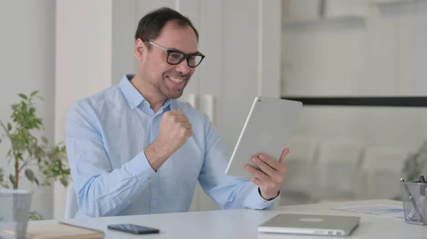 Homem de meia-idade comemorando no Tablet no escritório — Fotografia de Stock