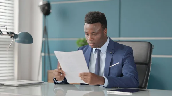 Afrikansk affärsman Läsa dokument när du sitter i Office — Stockfoto