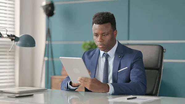 Homme d'affaires africain utilisant la tablette tout en étant assis dans le bureau — Photo