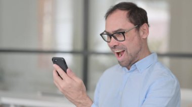 Orta Yaşlı Adam Akıllı Telefonla Kutlama Yapıyor