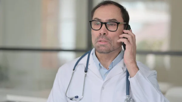 Medelålders doktor pratar på smartphone — Stockfoto