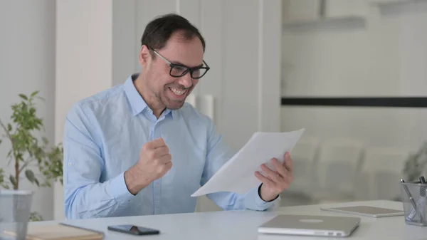 Erfolgreicher Mann mittleren Alters liest Dokumente — Stockfoto