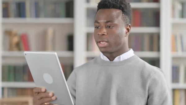 Porträtt av Video Call on Tablet av afrikansk man i biblioteket — Stockfoto
