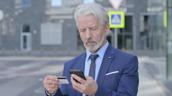 Velho Empresário Compras Online no Smartphone enquanto está de pé ao ar livre — Fotografia de Stock
