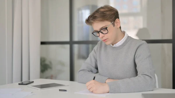 Jeune homme écrivant sur le papier dans le bureau moderne — Photo