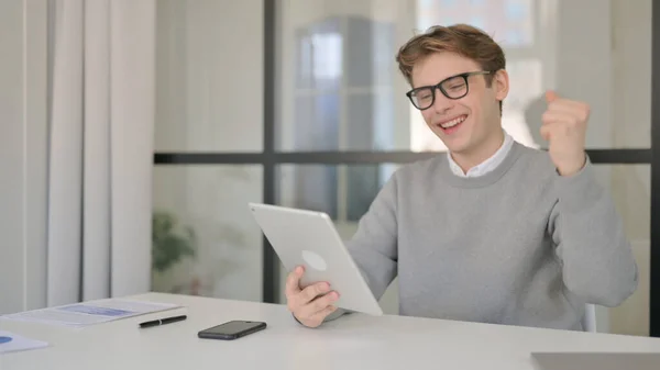 Joven celebrando el éxito en la tableta en la oficina moderna — Foto de Stock