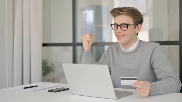 Hombre joven haciendo el pago en línea con éxito en el ordenador portátil — Foto de Stock