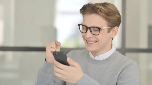Молодой человек празднует на смартфоне — стоковое фото