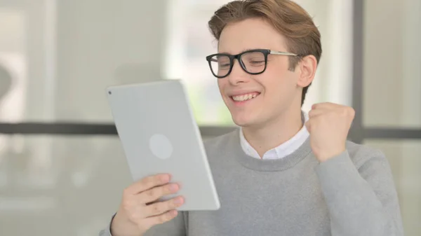 Junger Mann feiert auf Tablet im modernen Büro — Stockfoto