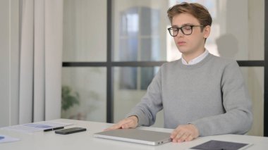 Genç Adam Bilgisayarı Kapatıyor ve Modern Ofisten Çıkıyor