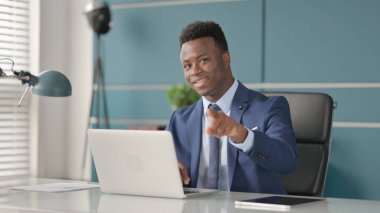 Ofiste dizüstü bilgisayar kullanırken Afrikalı İşadamı Kamerayı işaret ediyor