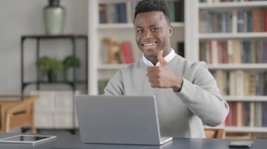 İş yerinde dizüstü bilgisayar kullanırken Afrikalı Adam İşaretini Gösteriyor 