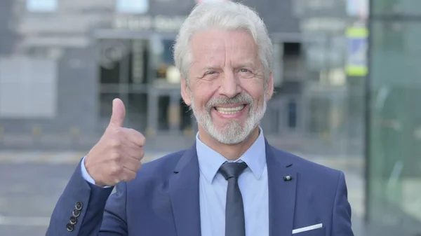 Thumbs Up by Old Businessman while Standing Outdoor