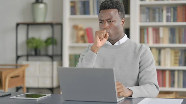非洲男子在图书馆使用笔记本电脑时咳嗽 — 图库照片