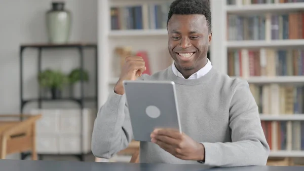 Africký muž slaví úspěch na tabletu v knihovně — Stock fotografie
