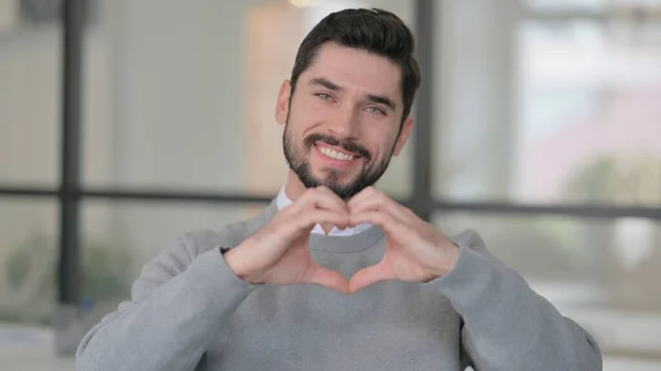 Retrato de un joven mostrando la forma del corazón con las manos — Foto de Stock