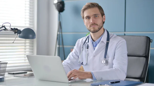 Läkare med laptop Titta på kameran på kliniken — Stockfoto