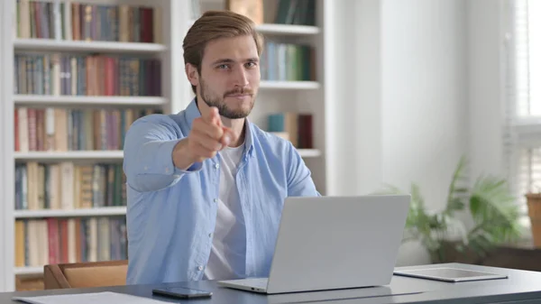 Hombre señalando a la cámara mientras usa el ordenador portátil en la oficina — Foto de Stock