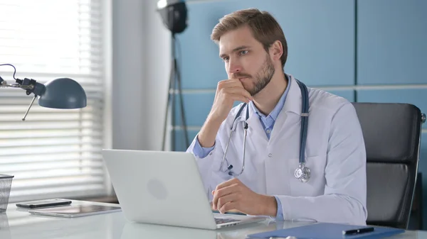 診療所でノートパソコンを使いながら考える医師 — ストック写真