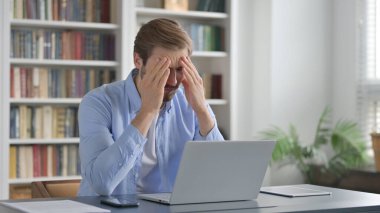 Ofiste dizüstü bilgisayar kullanırken Kayıplara Tepki Veren Adam