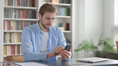 Ofiste akıllı telefon kullanan çekici adam. 