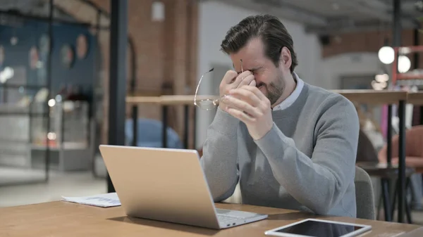 Junger Mann hat Kopfschmerzen bei der Arbeit am Laptop — Stockfoto